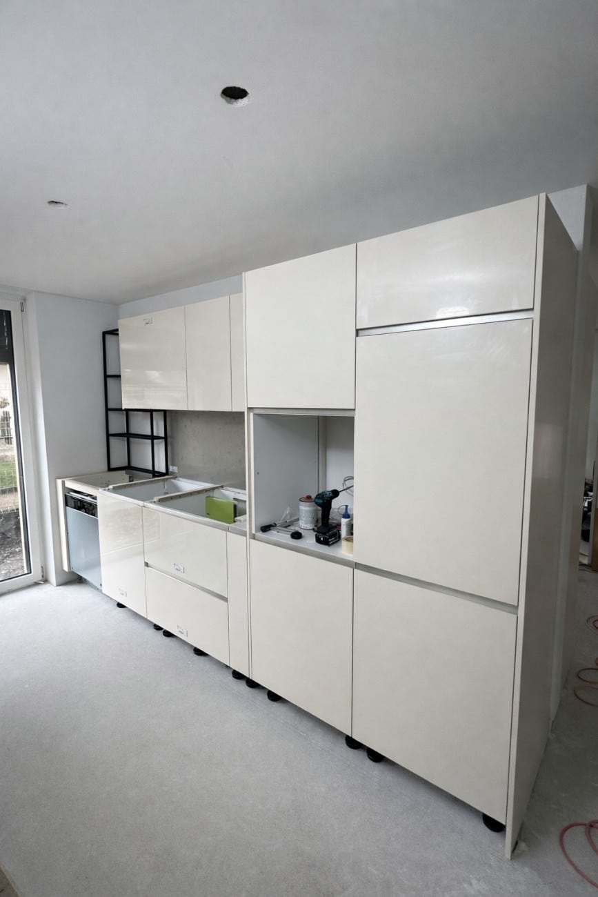 Moderne unvollständige Küche in Weißlack mit offenen Geräten und Arbeitsflächen, vorbereitet für Küchenmontage.