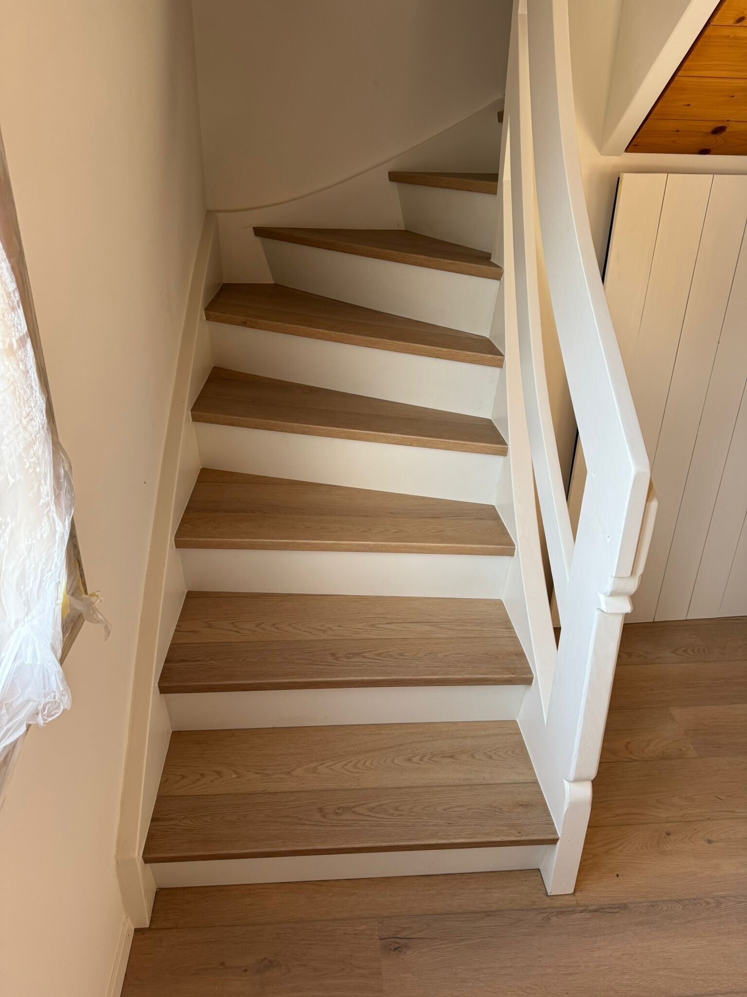 Holztreppe mit weißen Wangen und abgerundeten Stufen in modernem Wohnstil.