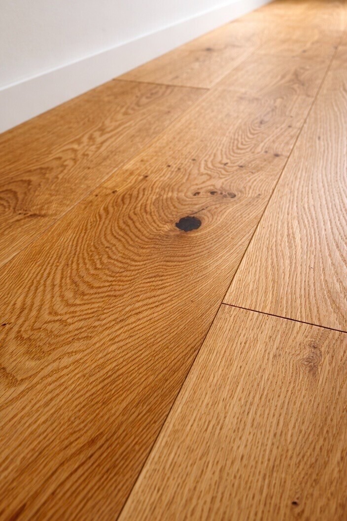 Nahaufnahme von hochwertigem, massivem Eichenparkettboden in natürlichem Holzton.