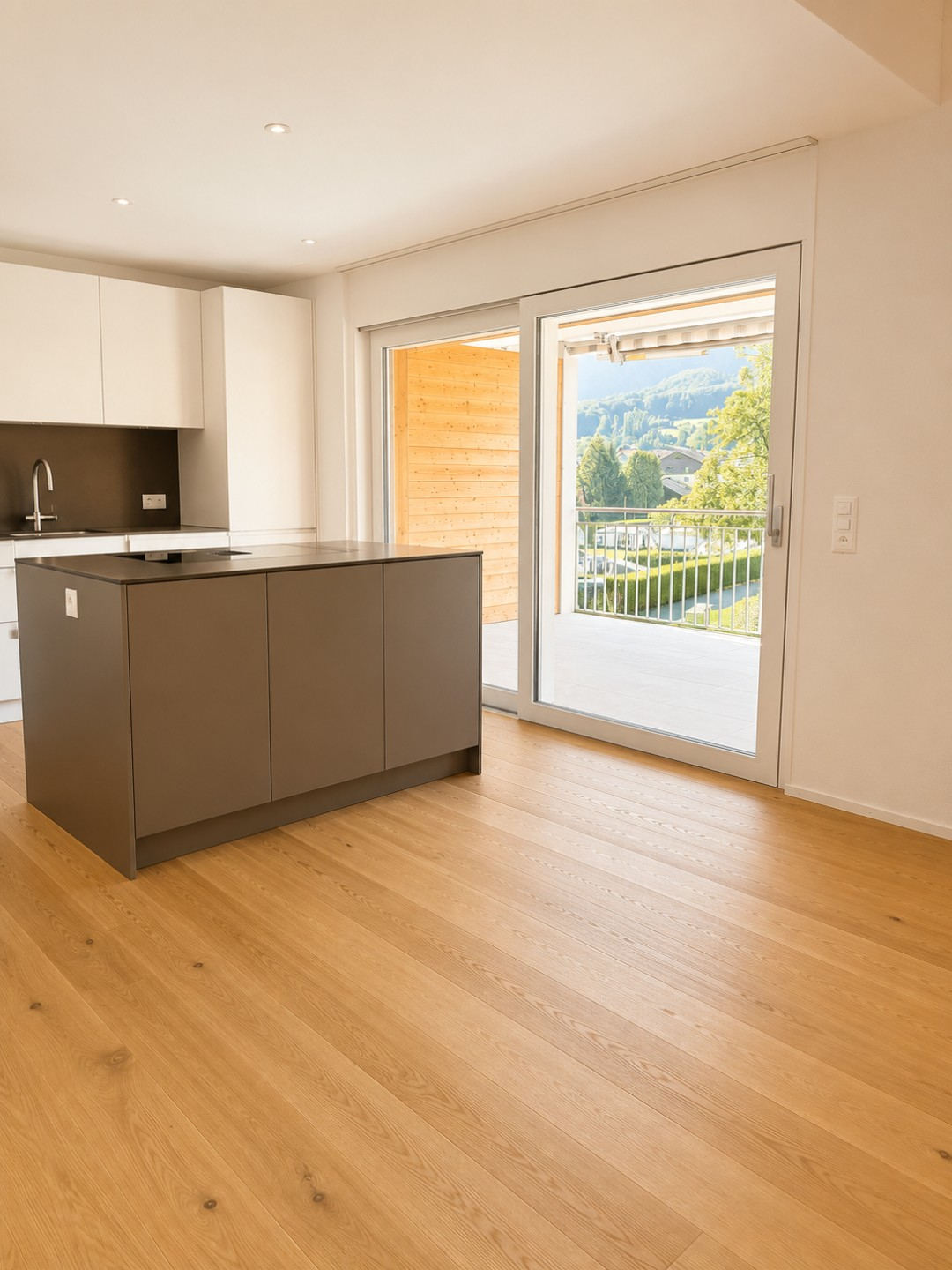 Moderne Küche mit Insel, Holzboden und großen Fenstern bietet Ausblick auf idyllische Landschaft.